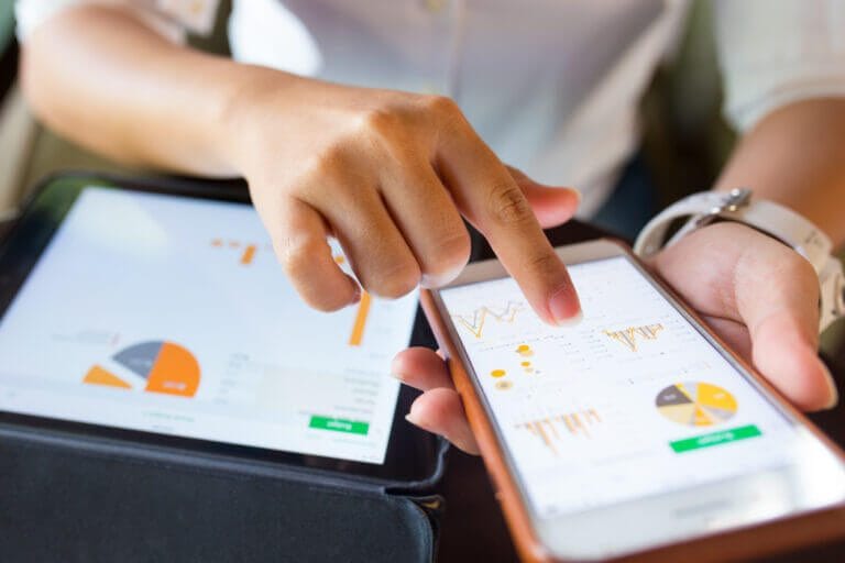 Woman looking at graphs and charts on mobile device and tablet.