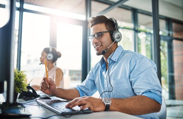 Two employees sitting at computers with headsets.