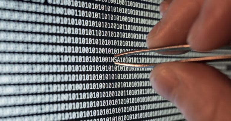 Tweezers pinching the phrase NSA in a series of computer code.