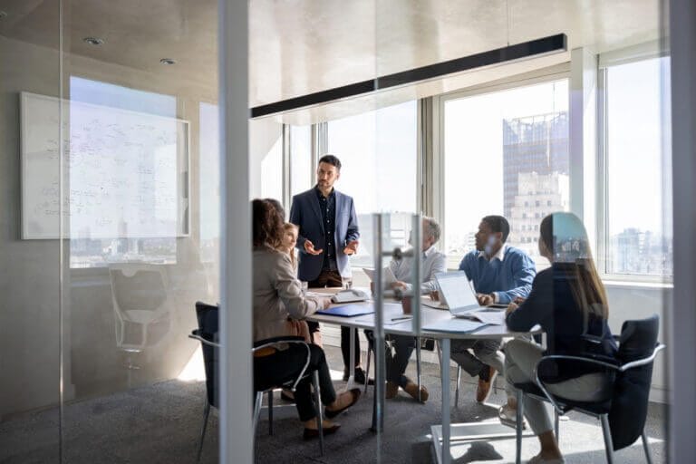 Employees meeting in a glass conference room about IT services and cybersecurity.