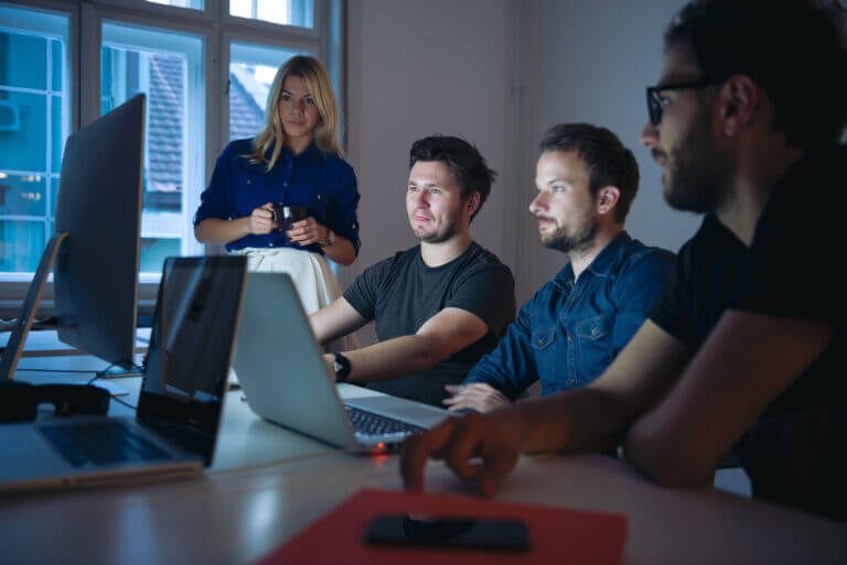 Employees gathered around a computer reviewing IT managed services and cybersecurity.