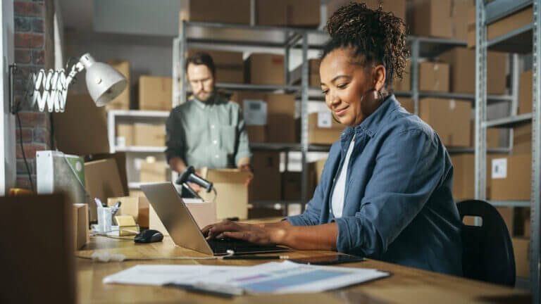 Woman working at her laptop in a fulfillment center.