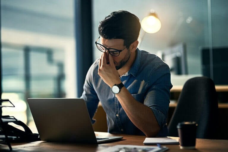 Man with his head in his hands reviewing cybersecurity strategies.