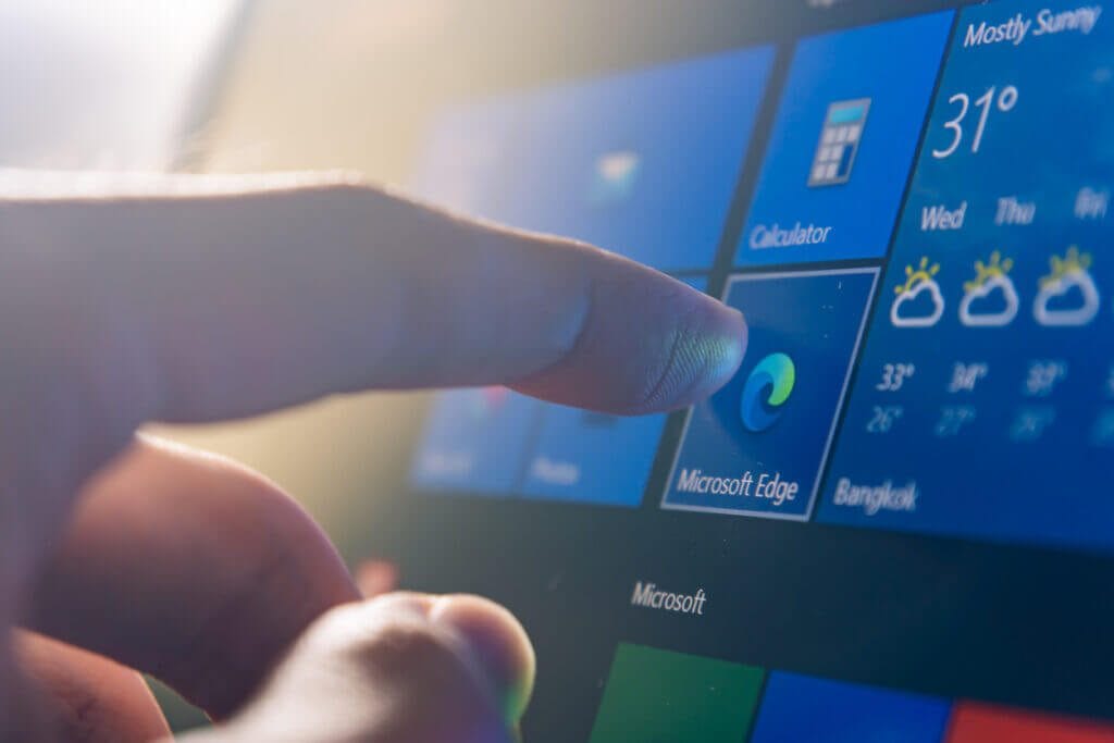 Hand touching Microsoft Edge app on a mobile device.