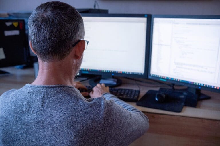 Man working on IT projects with dual monitors.