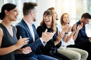 Co-workers sitting together and applauding in a meeting.