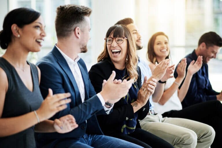 Co-workers sitting together and applauding in a meeting.