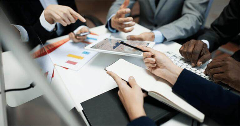 Employees sitting around a conference table working together on IT projects.