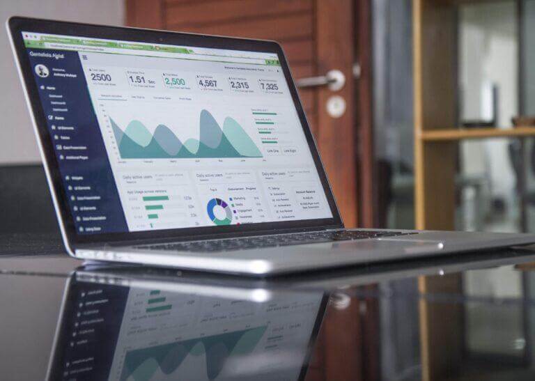 Laptop with software IT reporting and charts loaded on screen.