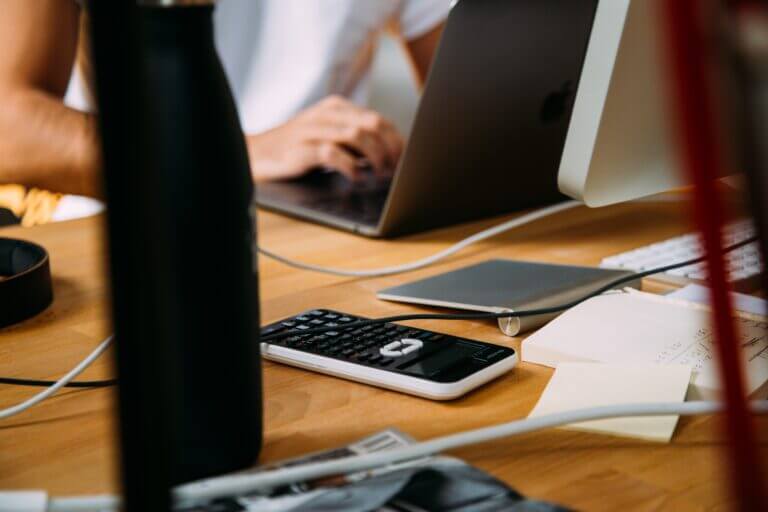 Employees working together at a conference desk with laptops and mobile devices.