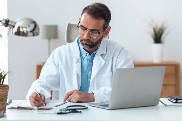 Male doctor working at desk computer.