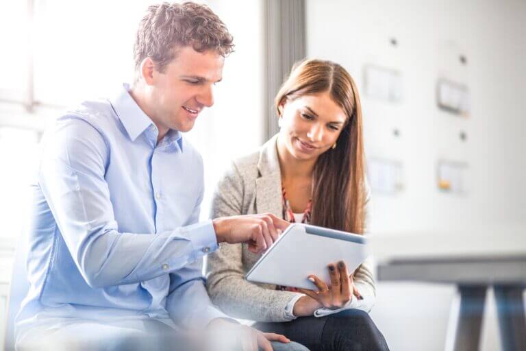 Two young business people reviewing documents on a tablet.
