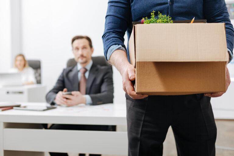 Employees watching a colleague pack up and leave the office.