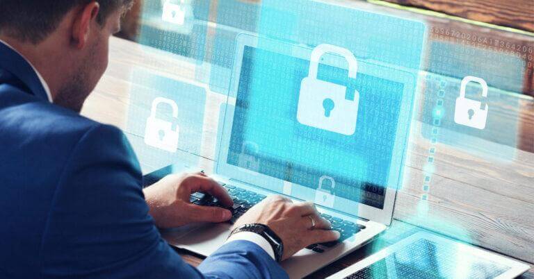 IT staff working at a laptop with a picture of a cyber lock on the screen.