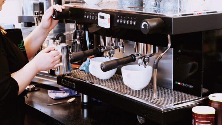 Barista steaming milk at an espresso machine.