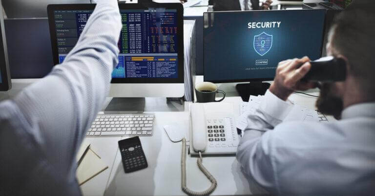 IT staff reviewing cybersecurity policies in a white office room.