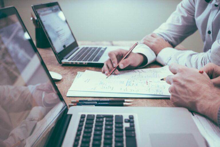 Two employees working together on a plan in a meeting.