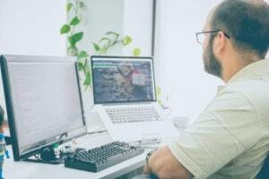 IT employee working at a laptop and computer.