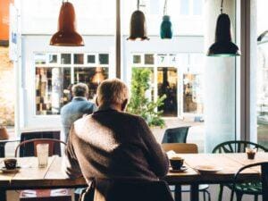 Older gentleman sitting at a long table with coffee cups.