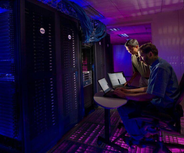 Science in HD- two men working on computers in front of a server