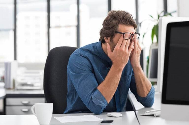 IT staff with head in hands at his office desk.