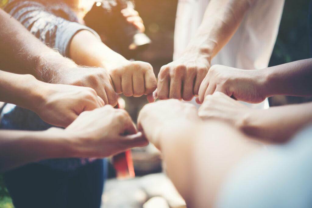 People with outstretched hands closed in fists.