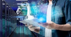 IT employee holding ipad and managing AI robotics equipment.
