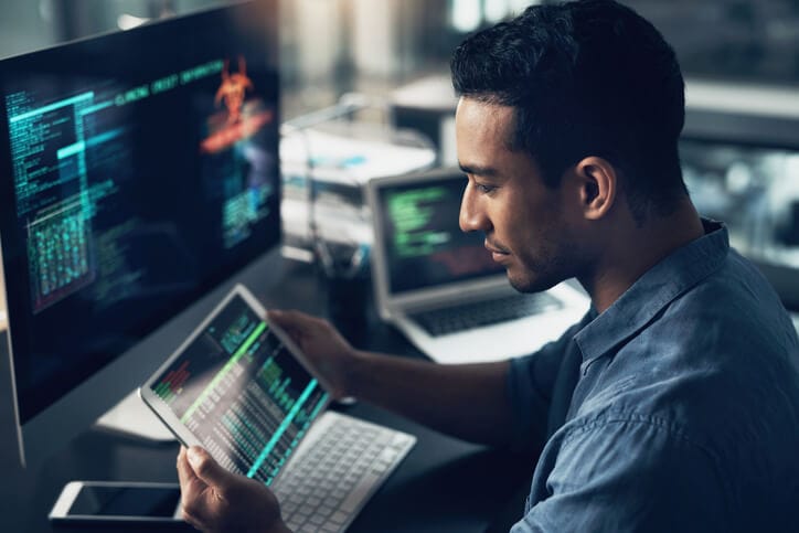 IT consultant working on a tablet, laptop and desktop computer.