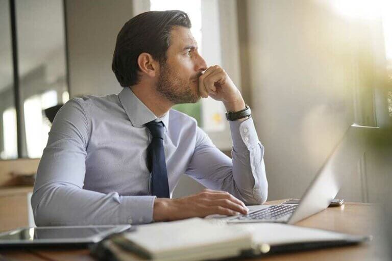Business man sitting at desk looking out a window.