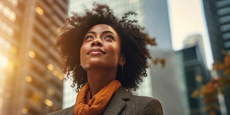 Young woman in city looking up at the sky.
